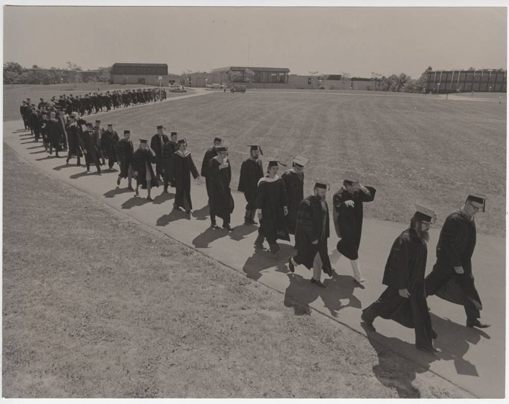 Image 1 of 8 Students walking in their cap and gown.